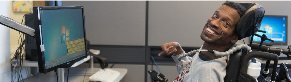 young man with cerebral palsy smiling in a computer lab